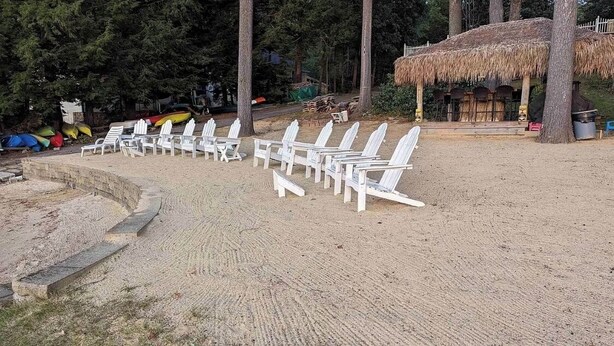 A sandy beach area with white lounge chairs arranged in rows.