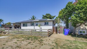 A single-story house with a fenced yard, a solar panel on the roof, and a blue trash bin. - San Diego Apartment w/ Patio - Near Balboa Park! (San Diego)