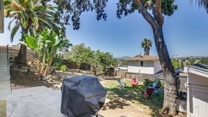 A backyard with a barbecue grill, palm trees, and a house in the background. - San Diego Apartment w/ Patio - Near Balboa Park! (San Diego)
