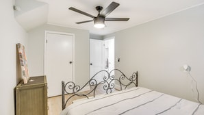 A bedroom with a bed, a ceiling fan, a door, and a small wooden cabinet. - San Diego Apartment w/ Patio - Near Balboa Park! (San Diego)