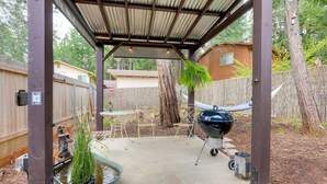 Un patio coperto con barbecue, mobili da esterno e un elemento d'acqua.