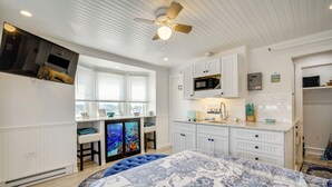 A bedroom with a large bed, a ceiling fan, a TV, and a kitchenette with a microwave and sink. - Ocean City Hideaway: Walk to Boardwalk & Beach! (Ocean City)