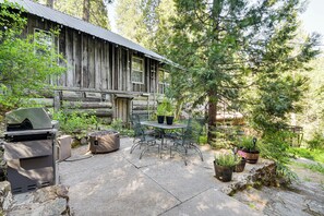 A rustic cabin with a stone patio, outdoor seating, and potted plants. - 8 Mi to Yosemite National Park: Cabin w/ Fire Pit (Oakhurst)