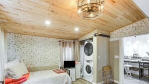 A bedroom with a bed, a washing machine, and a small kitchenette. - Cozy Carterville Home: 3 Mi to Crab Orchard Lake! (Carterville)