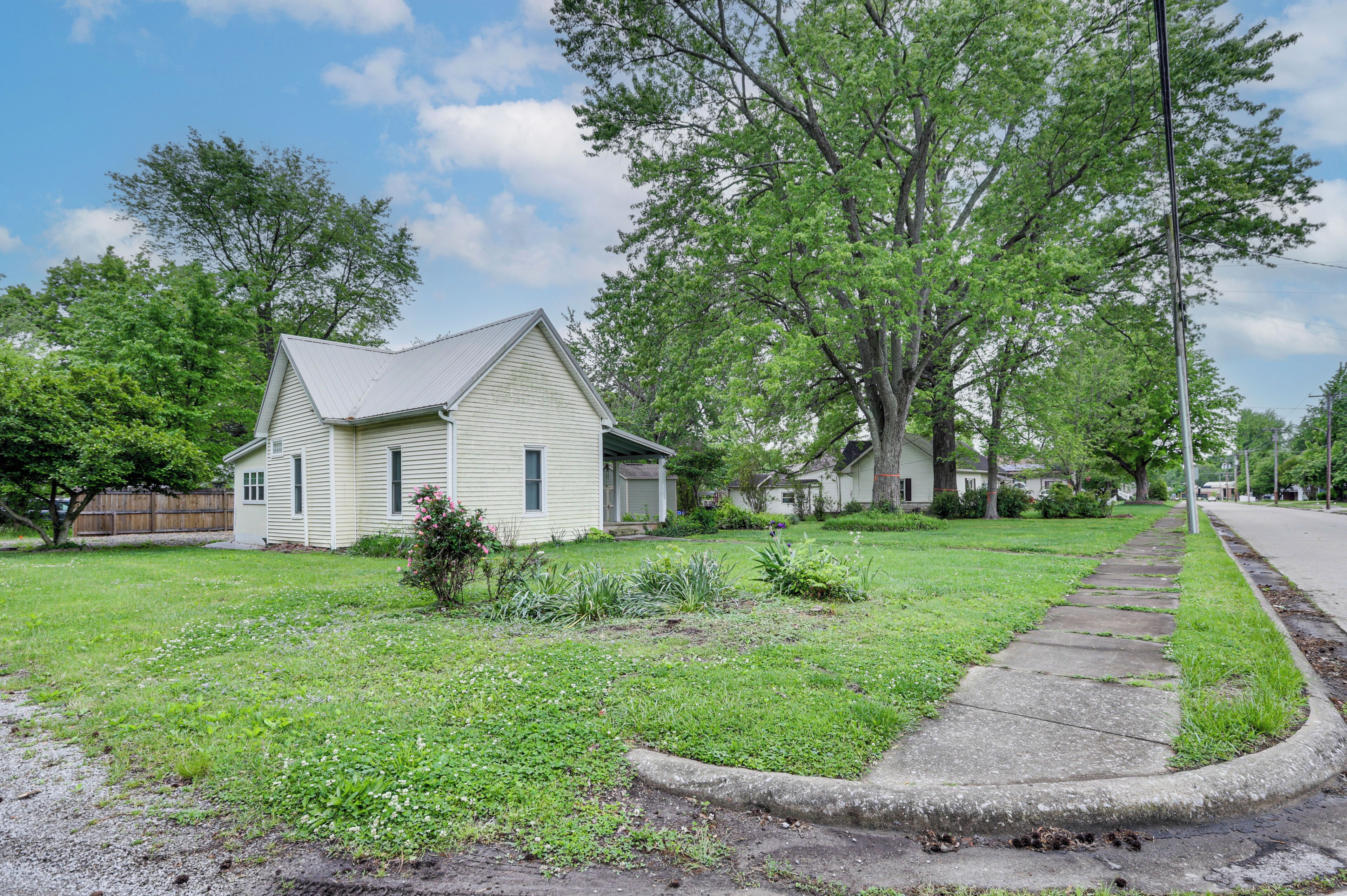 A residential area with a single-story house, a well-maintained lawn, and a sidewalk.
