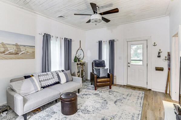 A living room with a sofa, armchair, and a ceiling fan.