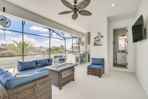 Un ampio balcone con mobili in vimini e una ventola a soffitto, con vista su una zona residenziale.