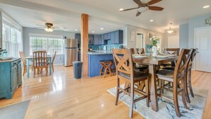 A spacious kitchen with wooden flooring, a dining area with a table set for four, and a central island. - Riverfront Cheboygan Home w/ Dock ~ 4 Mi to Town! (Cheboygan)