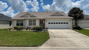 A single-story house with a garage, a well-maintained lawn, and a clear sky. - Private Pool Paradise close to Lake Sumter Landing Market Square! (The Villages)