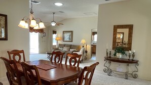 A dining area with a wooden table and chairs, a ceiling fan, and a chandelier. - Private Pool Paradise close to Lake Sumter Landing Market Square! (The Villages)