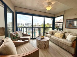 Ein geräumiger Balkon mit Korbmöbeln, einem runden Holztisch und Blick auf den Hafen und die Gebäude.