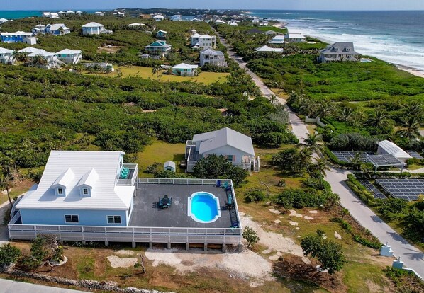 A coastal property with a swimming pool, solar panels, and a view of the ocean.