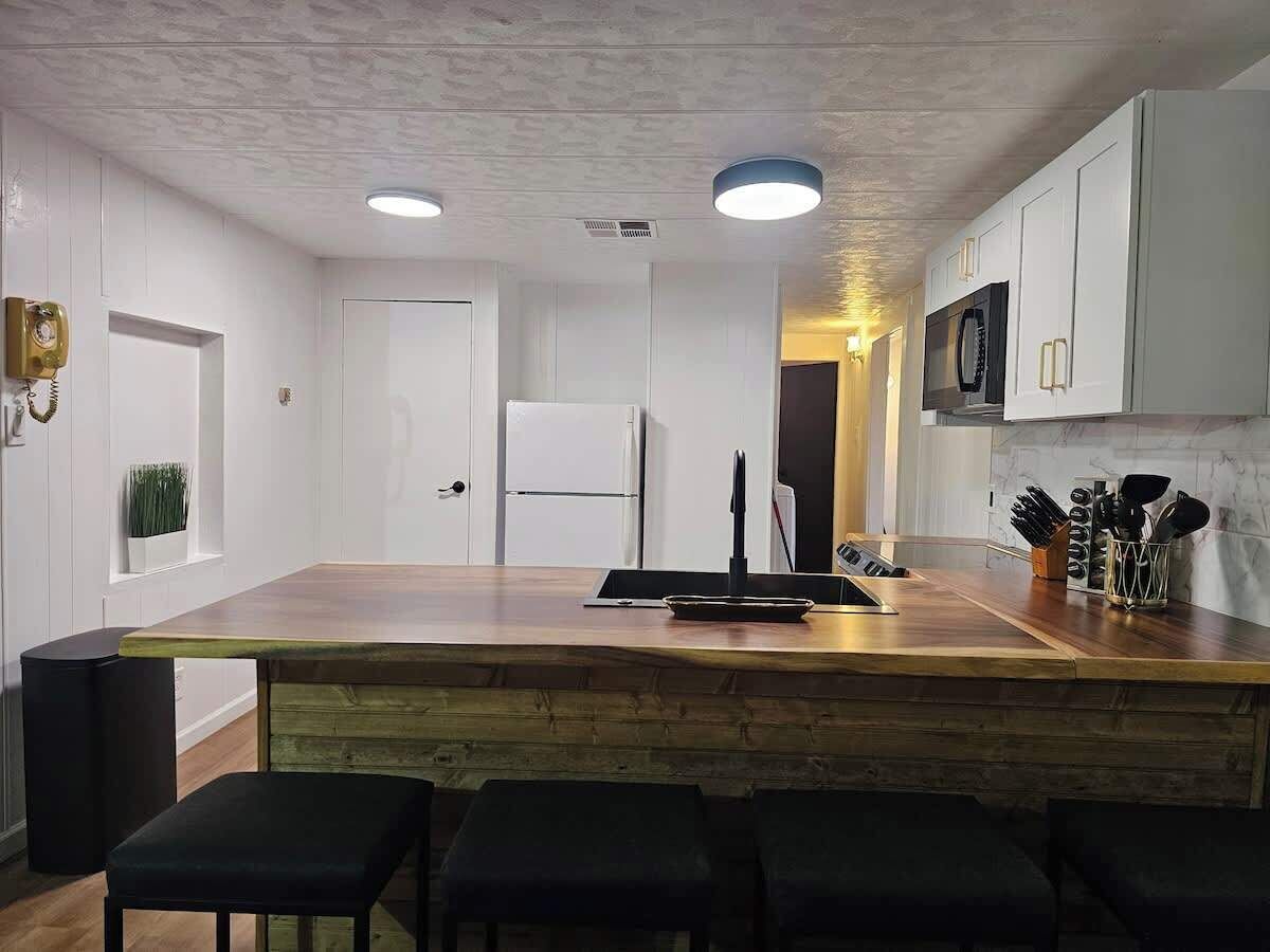 A modern kitchen with white cabinets, a wooden island, and bar stools.