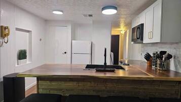 A modern kitchen with white cabinets, a wooden island, and bar stools.