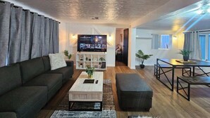 A modern living room with a sofa, coffee table, and TV. There is a staircase leading to another level. - Stargaze Grand Canyon (Meadview)