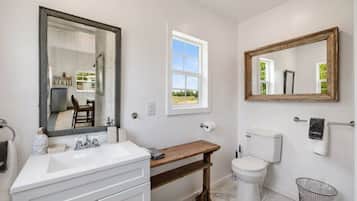 Une salle de bain avec un grand miroir, une fenêtre, des toilettes et un lavabo.