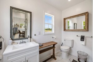 Een badkamer met een grote spiegel, een raam, een toilet en een wastafel.