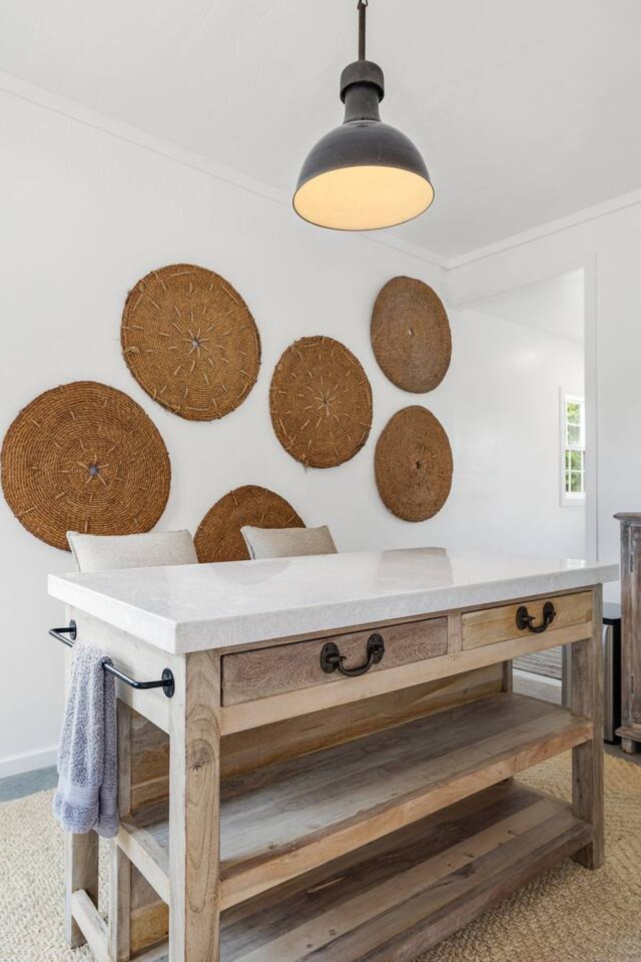 Een kamer met een witte tafel, houten lades en een hanglamp.