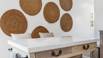 Une pièce avec une table blanche, des tiroirs en bois et un luminaire suspendu.