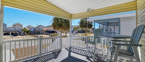 A covered porch with a view of a residential area, including houses and a street.