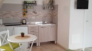 Une cuisine compacte équipée d’un évier, d’une cuisinière et d’un petit coin repas avec une table et des chaises.