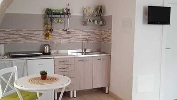 A compact kitchen with a sink, stove, and a small dining area with a table and chairs.