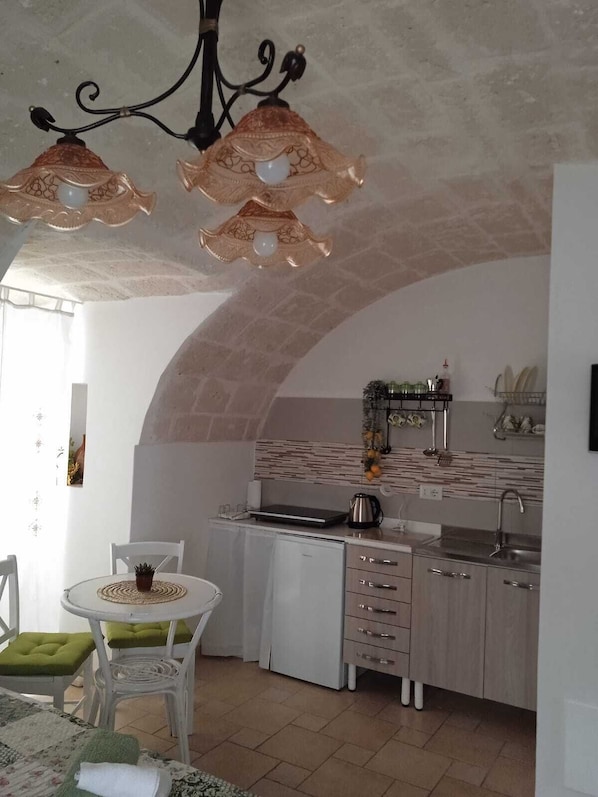 A compact kitchen with a white countertop, a sink, and a stove. There is a dining area with a table and chairs.