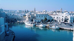 Un port où sont amarrés des bateaux, une tour de l’horloge et des bâtiments qui bordent la rive.