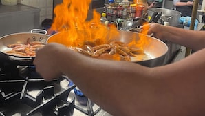 Une cuisine équipée d’une cuisinière, de casseroles et d’une personne qui prépare des crevettes.