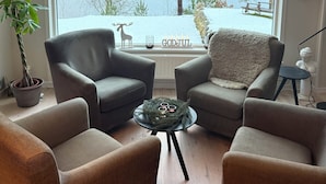 A living room with two grey armchairs, a small round table, and a large window overlooking a lake. - House with fantastic view and direct access to the lake and boat. (Skåne län)