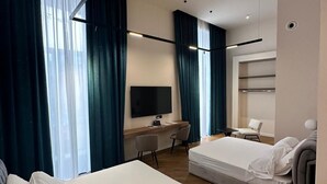 A modern hotel room with two beds, a desk, a TV, and a large window with curtains. - MAISON TOLEDO - Boutique Suites (Naples)
