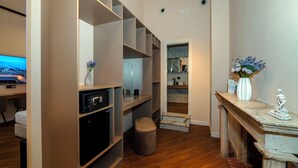A modern interior with a wooden floor, built-in shelving, a television, and a fireplace. - MAISON TOLEDO - Boutique Suites (Naples)