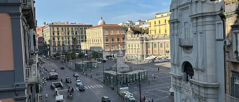 A city street with historic buildings, a large open square, and a prominent white monument.