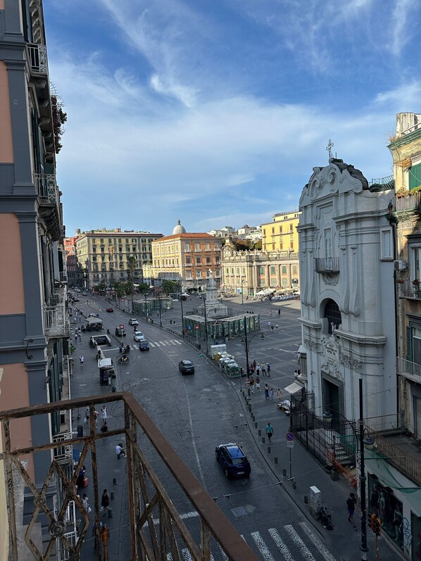 A city street with historic buildings, a large open square, and a prominent white monument.