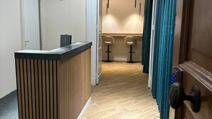 A modern reception area with a wooden reception desk, a counter, and two bar stools. - MAISON TOLEDO - Boutique Suites (Naples)