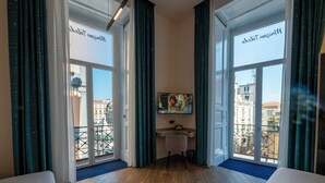A hotel room with large windows, a desk, and a chair. - MAISON TOLEDO - Boutique Suites (Naples)