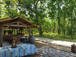 Un espace extérieur aménagé dans un style rustique, avec une pergola en bois, un sol carrelé en pierre et un four à pizza.