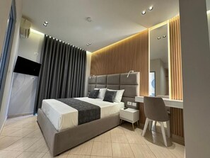 A modern bedroom with a bed, bedside table, chair, and a large mirror. - Villa CACA (Ksamil)