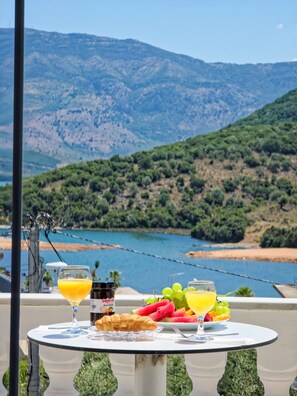 A table with food and drinks, a view of a lake and mountains. - Villa CACA (Ksamil)