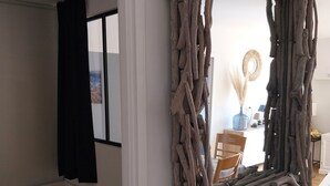 Ein Zimmer mit einem Bett, einem Spiegel mit Holzrahmen, einem Schreibtisch mit Stuhl und einem Fenster mit Vorhängen.