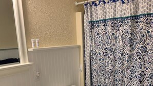 Un baño con lavamanos blanco, inodoro y cortina de ducha con estampado azul y blanco.