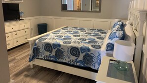 Un dormitorio con cama, cómoda, televisor y espejo.