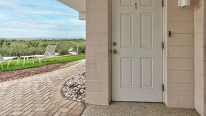 A white door with a keyhole and a peephole, leading to a covered patio area with a view of the ocean and beach. - Directly on the Gulf - Unit  1 - 3 Bedroom - Ground Floor - Sleeps 6 (Venice)