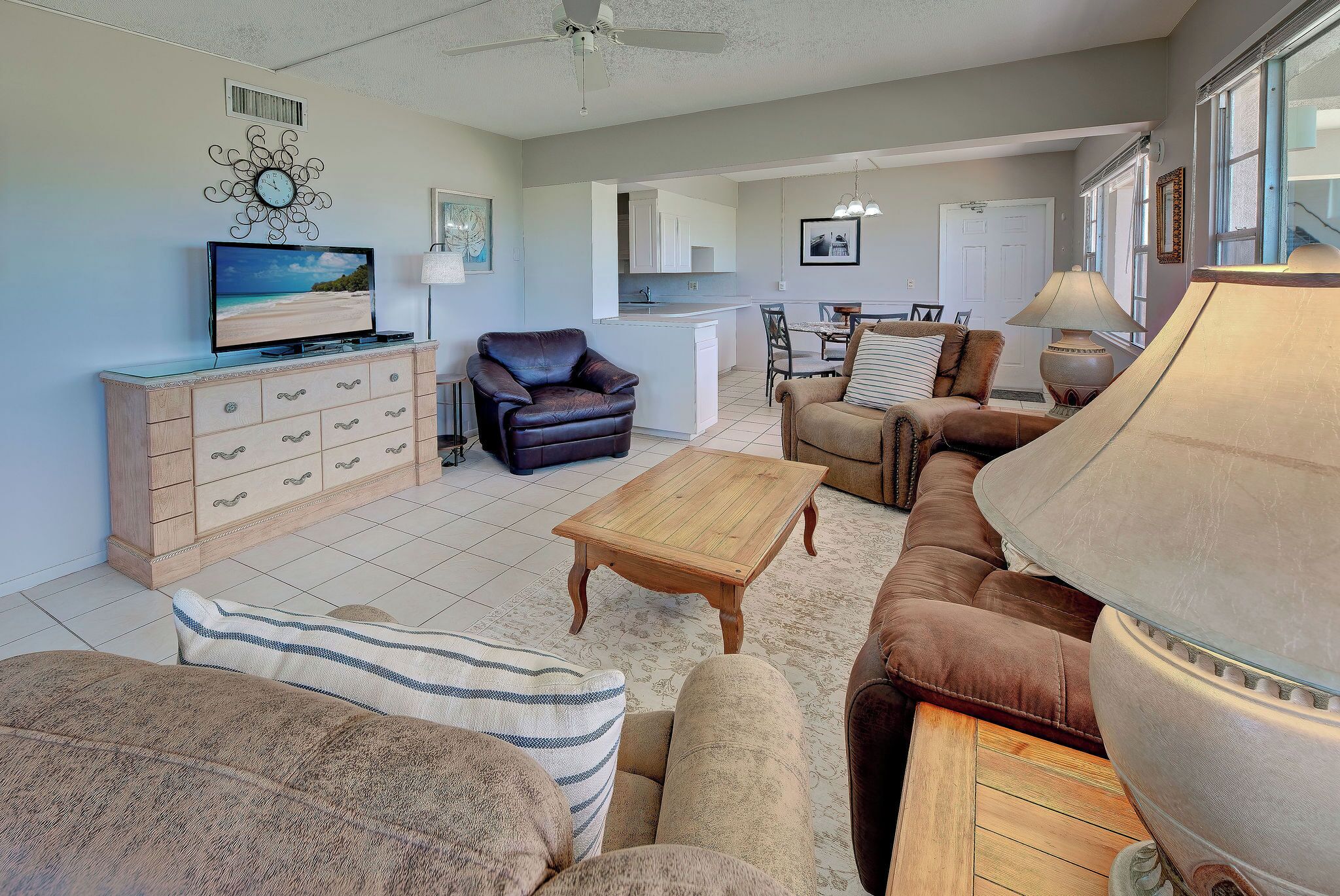 A living room with a television, sofas, a coffee table, and a dining area with chairs.