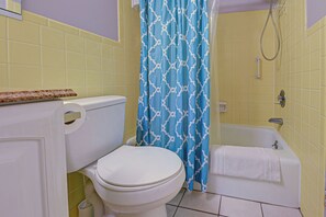 Une salle de bain équipée de toilettes, d’une baignoire et d’un rideau de douche.