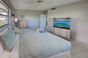 A bedroom with a bed, a dresser, a television, and a window.
