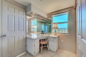 A bathroom with a vanity, a chair, a mirror, and a window with a view. - Directly on the Gulf - Unit  1 - 3 Bedroom - Ground Floor - Sleeps 6 (Venice)