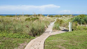 A paved pathway leading to a beach with grassy areas and some vegetation. - Directly on the Gulf - Unit  1 - 3 Bedroom - Ground Floor - Sleeps 6 (Venice)