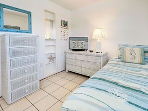 A bedroom with a bed, a dresser, a television, and a mirror.