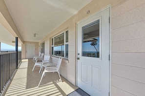 A covered balcony with white chairs and a door marked with the number 13.
